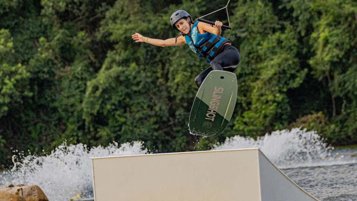 Rider andando no sistema de wake do Alpha Wake Park com lago e estrutura ao fundo